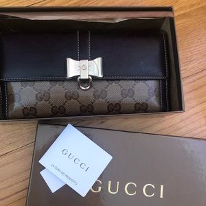 Monogram GG Gucci flap wallet with gold bow